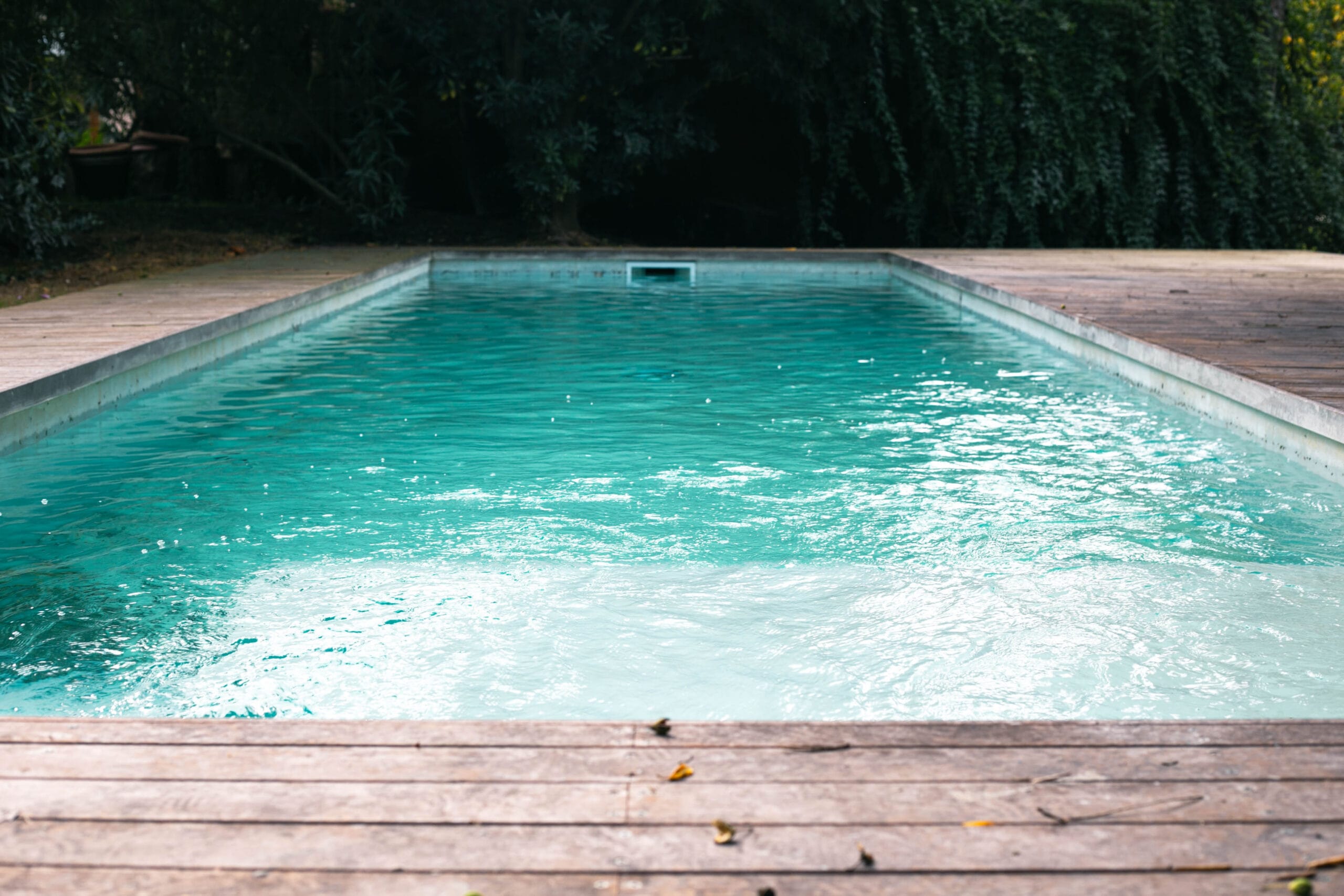 Piscina blanca con deck de madera en el patio del fondo de Tesore