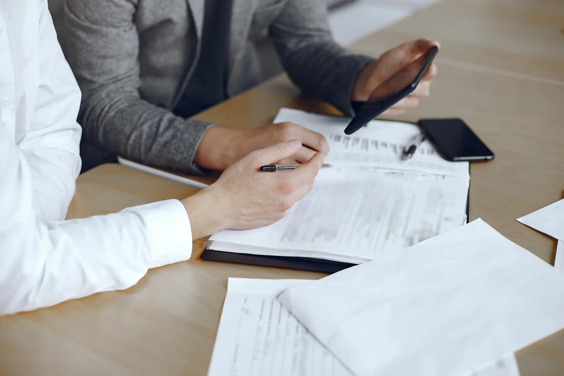 Dos abogados en una mesa firmando documentos sobre los requisitos legales para construir.