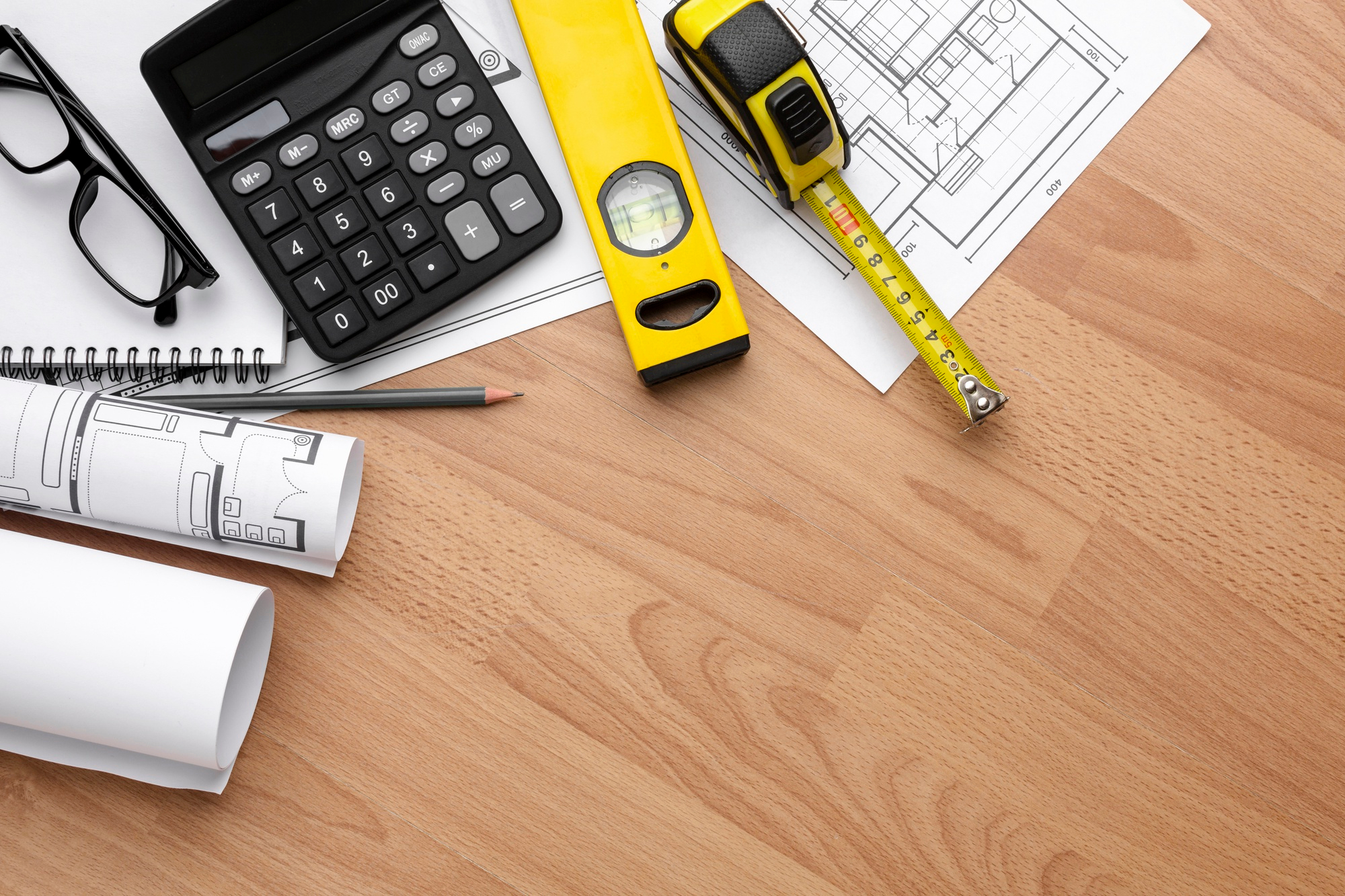 Imágen de planos, herramientas de medida y una calculadora sobre un escritorio