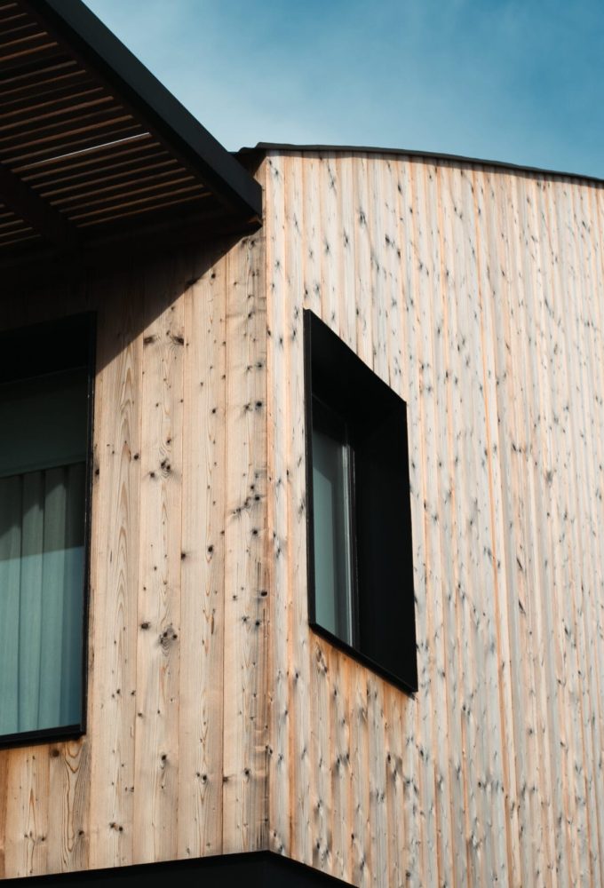 Foto de fachada de Pontelli destacando la madera tratada de las paredes exteriores y las ventanas con aluminio negro.