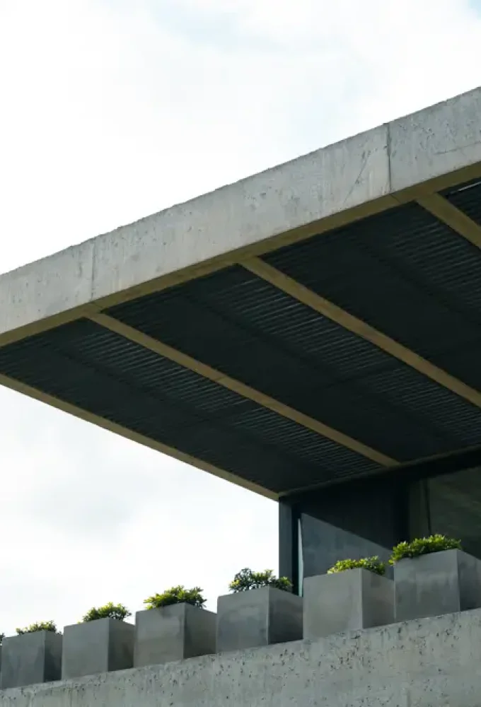 Balcon de piso 2 de Benu, donde se ven varias macetas de hormigón con plantas y una pérgola de madera