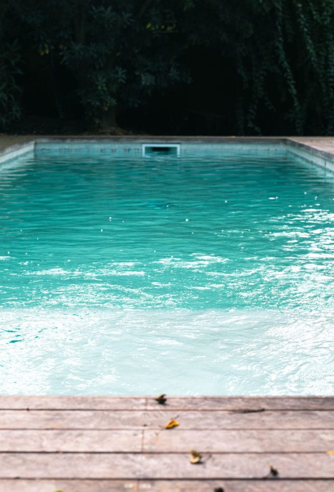 Piscina blanca con deck de madera en el patio del fondo de Tesore